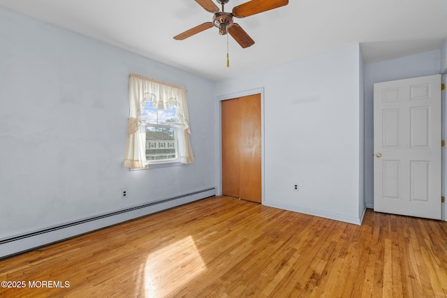 unfurnished bedroom featuring a baseboard heating unit, a closet, ceiling fan, and light wood-type flooring