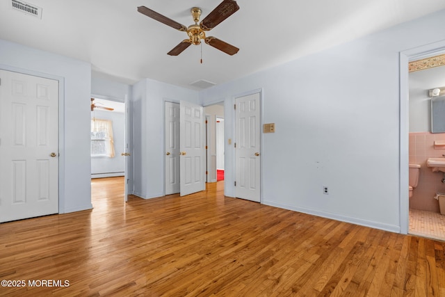 unfurnished bedroom with ensuite bath, a baseboard radiator, light hardwood / wood-style floors, and ceiling fan