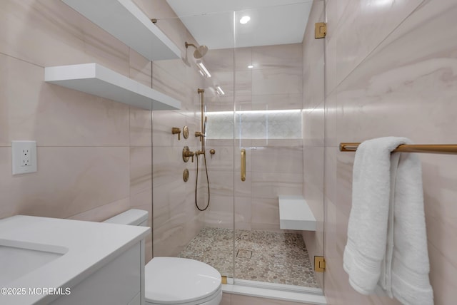 bathroom featuring toilet, tile walls, vanity, and walk in shower