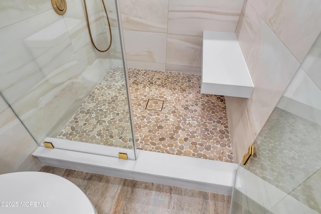 bathroom with a tile shower and toilet