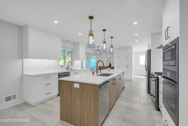 kitchen featuring a kitchen island with sink, sink, and white cabinets