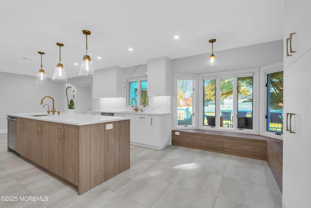 kitchen with sink, white cabinetry, dishwasher, pendant lighting, and a kitchen island with sink