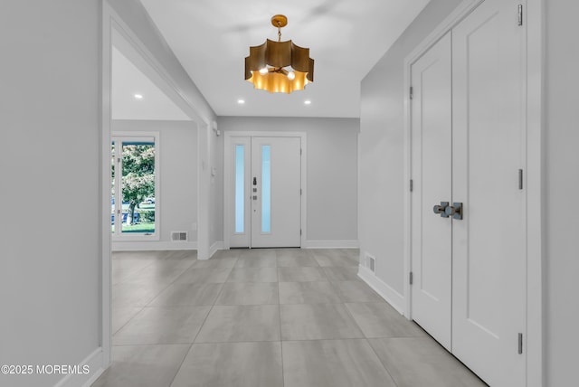 foyer entrance with light tile patterned flooring and a chandelier