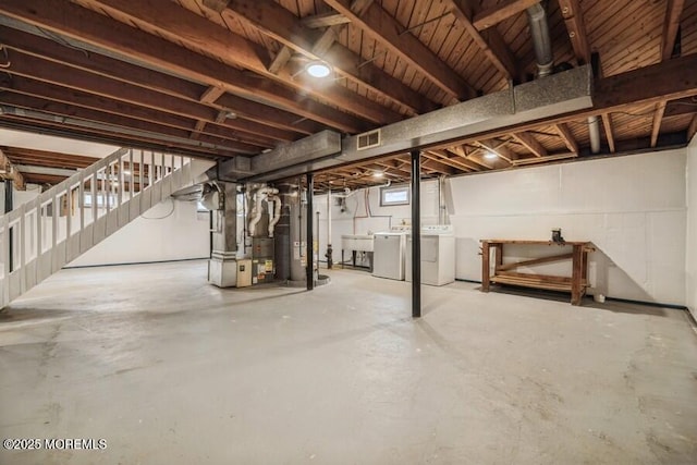 basement featuring washing machine and clothes dryer, sink, and heating unit