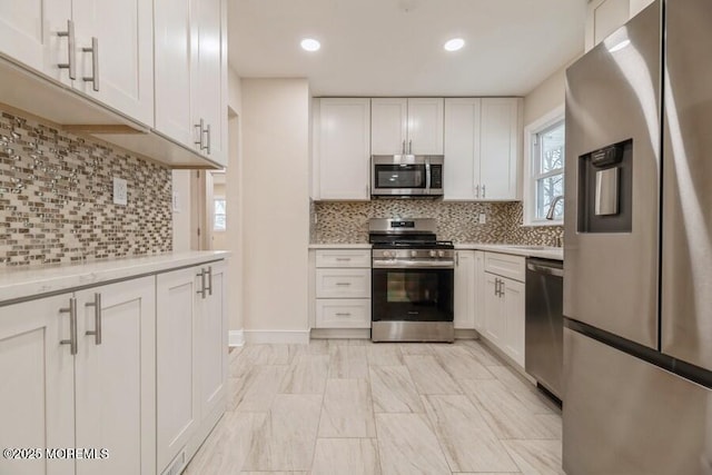 kitchen with sink, white cabinetry, stainless steel appliances, tasteful backsplash, and light stone countertops