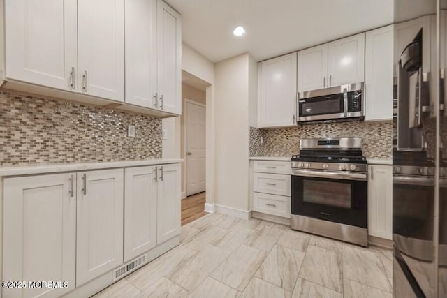 kitchen with stainless steel appliances, white cabinetry, and decorative backsplash