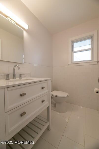 bathroom featuring vanity, toilet, and tile walls