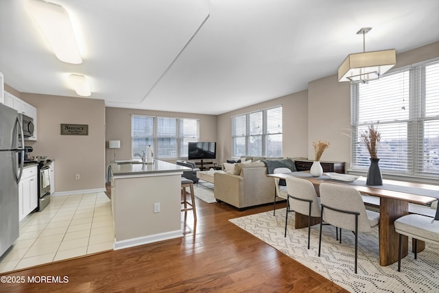 kitchen with white cabinetry, decorative light fixtures, light hardwood / wood-style floors, and appliances with stainless steel finishes