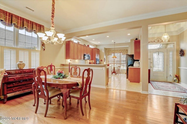 dining room featuring a notable chandelier, ornamental molding, and light wood-type flooring