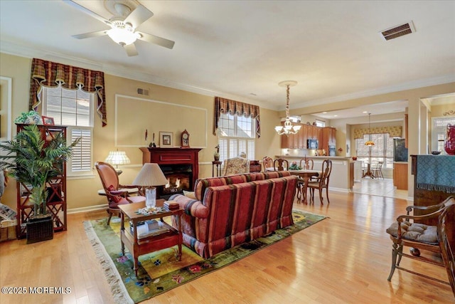 living room with ornamental molding, ceiling fan with notable chandelier, and light hardwood / wood-style flooring