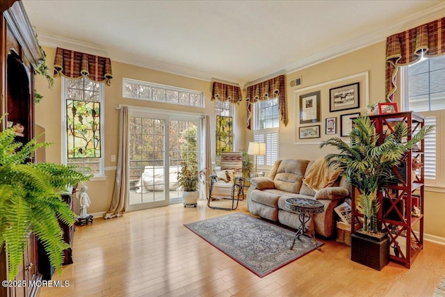 sitting room with a wealth of natural light, light hardwood / wood-style flooring, and ornamental molding