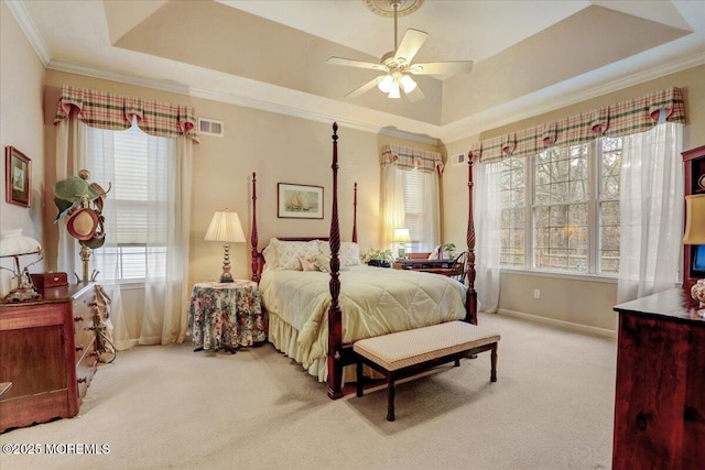 bedroom with light carpet, a tray ceiling, crown molding, and ceiling fan