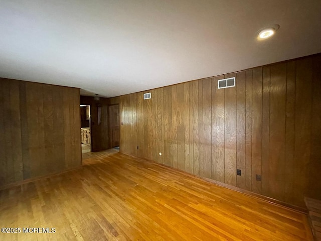 spare room with wooden walls and light hardwood / wood-style flooring