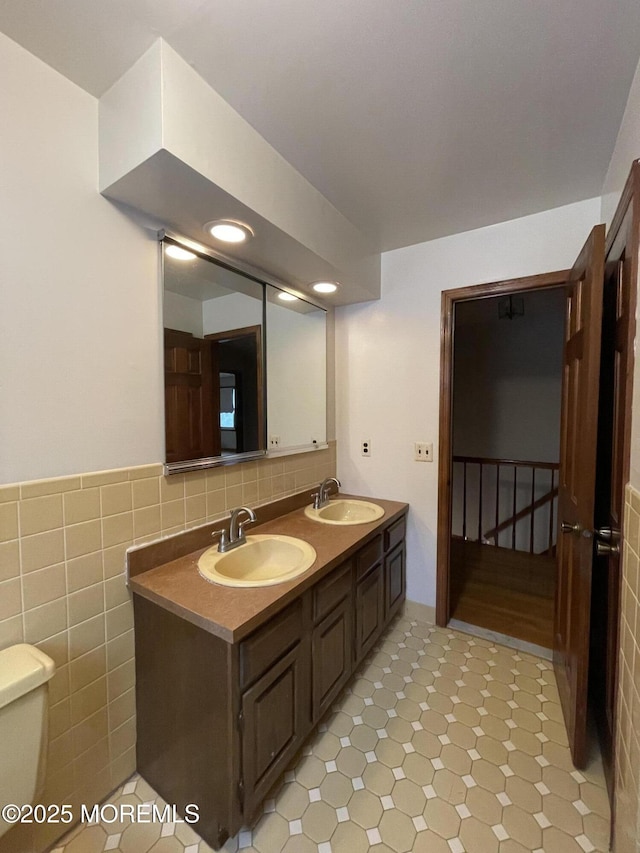 bathroom featuring vanity, toilet, and tile walls