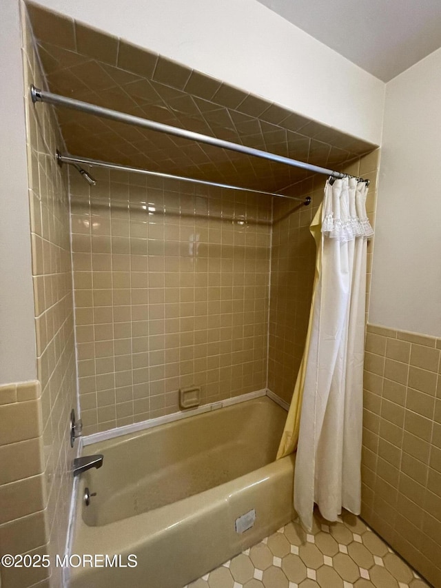 bathroom with shower / bathtub combination with curtain, tile patterned flooring, and tile walls