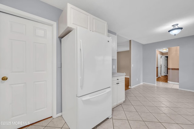 kitchen with white cabinetry, light tile patterned floors, and white fridge