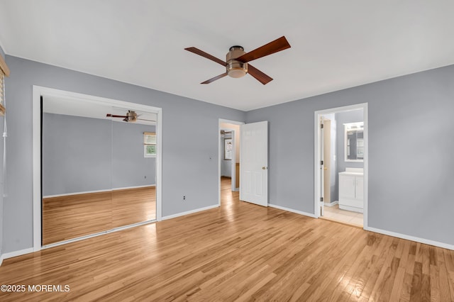 unfurnished bedroom featuring ceiling fan, ensuite bathroom, light hardwood / wood-style floors, and a closet