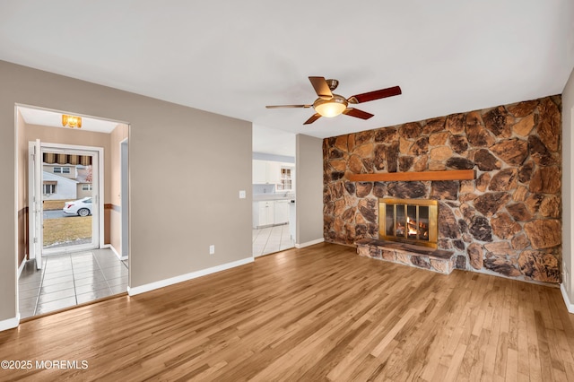 unfurnished living room with ceiling fan, a fireplace, and light hardwood / wood-style floors