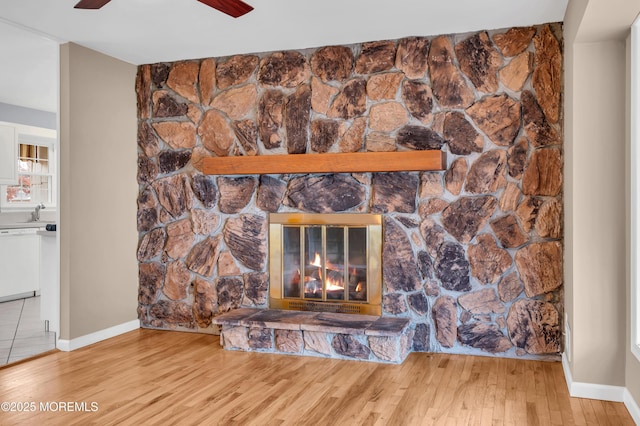 room details with white dishwasher, ceiling fan, a fireplace, and wood-type flooring