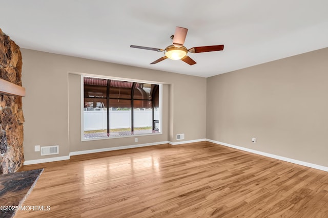 unfurnished living room with ceiling fan, a fireplace, and light wood-type flooring