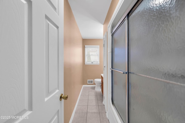 bathroom featuring an enclosed shower, tile patterned floors, and toilet