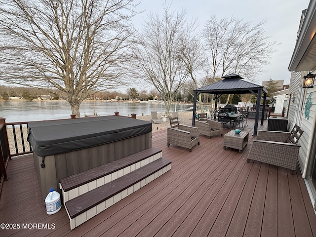 wooden deck featuring a water view, a covered hot tub, and a gazebo