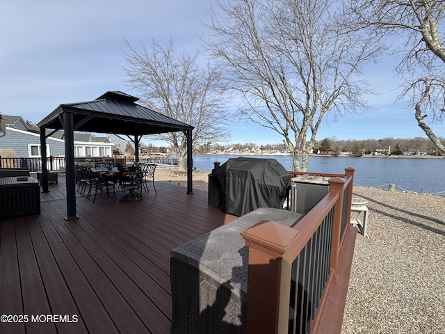 wooden terrace featuring a gazebo, outdoor dining space, grilling area, and a water view