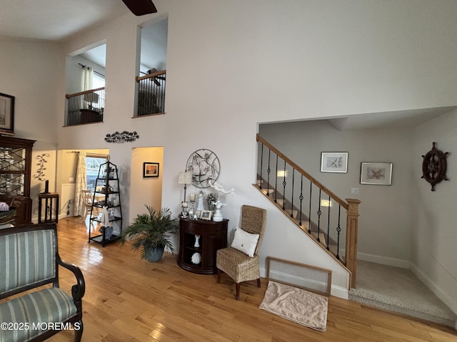 interior space featuring stairway, wood finished floors, a towering ceiling, and baseboards