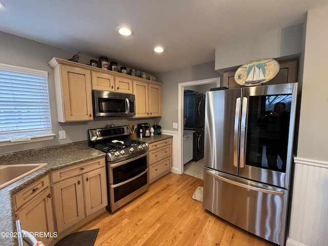 kitchen with dark countertops, recessed lighting, appliances with stainless steel finishes, light brown cabinets, and light wood-type flooring