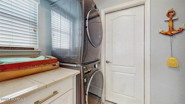 clothes washing area with stacked washer / dryer and cabinet space