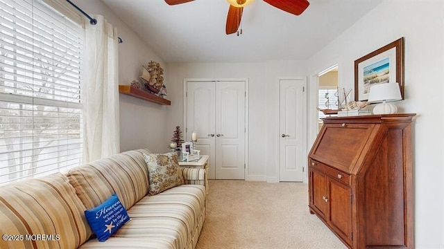 living area featuring a ceiling fan and light colored carpet