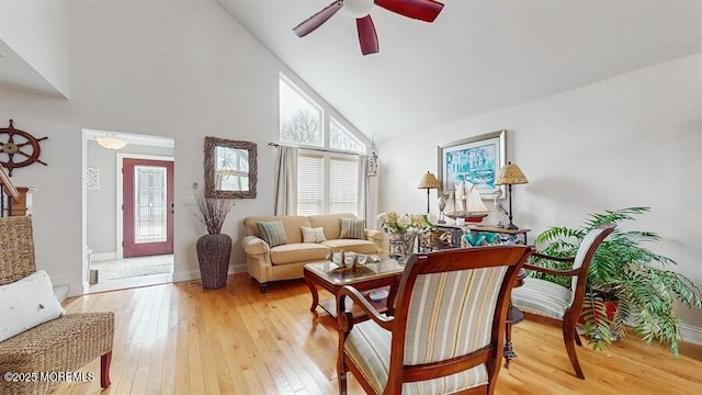 living area with light wood-style floors, a healthy amount of sunlight, high vaulted ceiling, and stairs