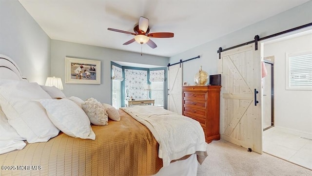 bedroom with a barn door, multiple windows, a ceiling fan, and light colored carpet