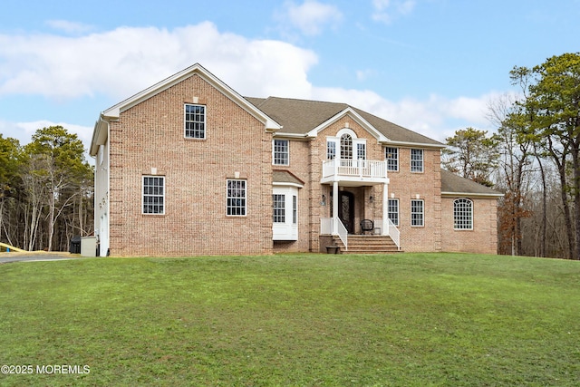 colonial inspired home with a balcony and a front lawn