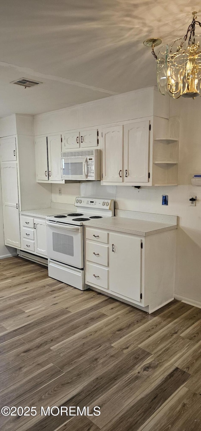 kitchen featuring decorative light fixtures, white cabinetry, a chandelier, dark wood-type flooring, and white appliances