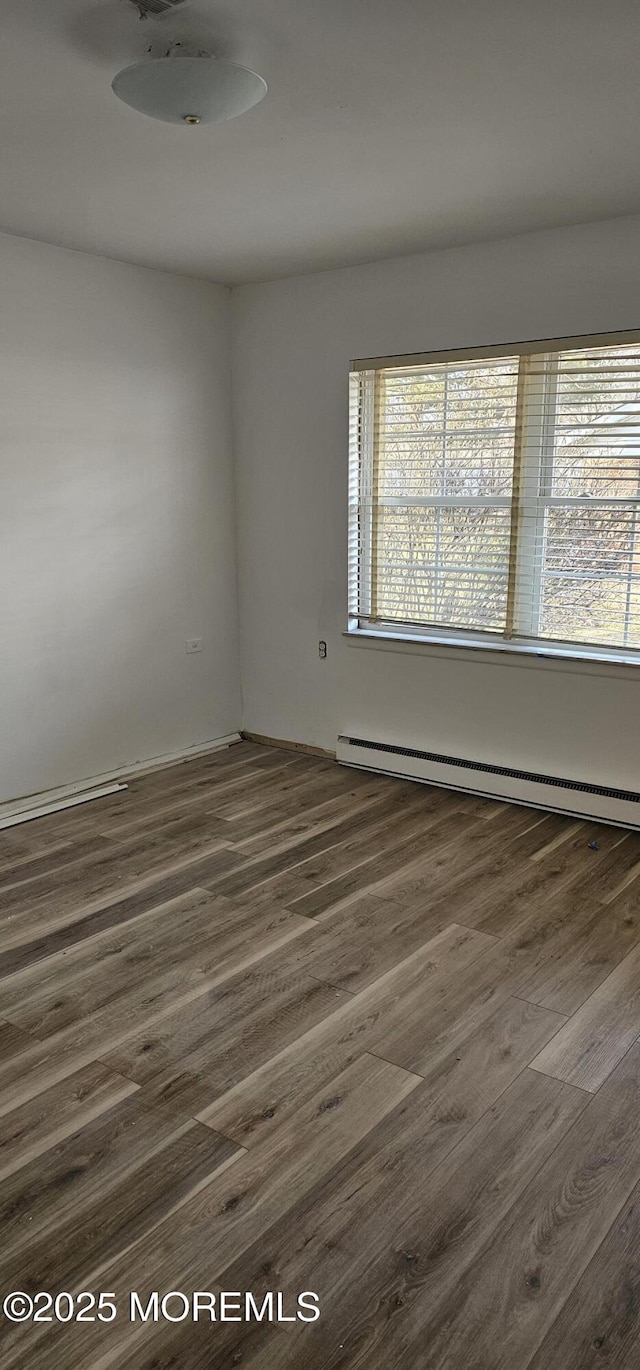 unfurnished room with a healthy amount of sunlight, dark hardwood / wood-style floors, and baseboard heating