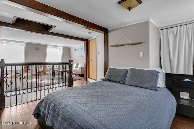 bedroom featuring hardwood / wood-style flooring, ornamental molding, and beam ceiling