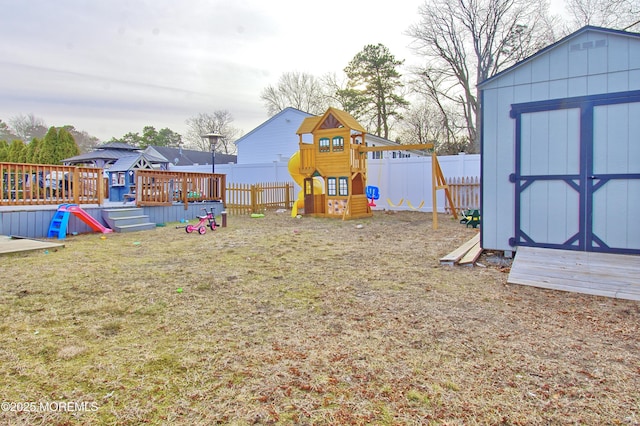 view of yard with a storage unit, a deck, and a playground