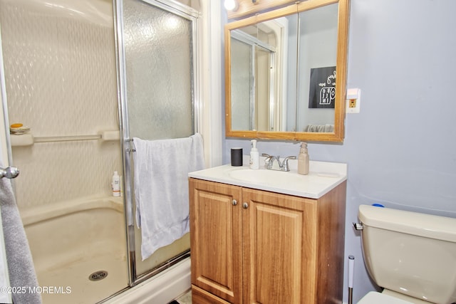 bathroom featuring toilet, vanity, and a shower with shower door