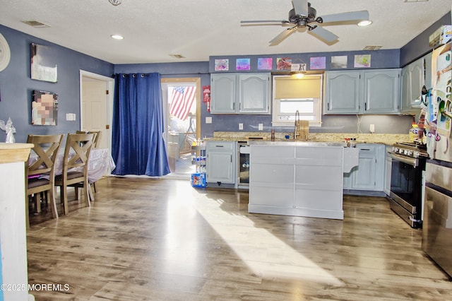 kitchen with hardwood / wood-style floors, stainless steel range with gas stovetop, and a textured ceiling