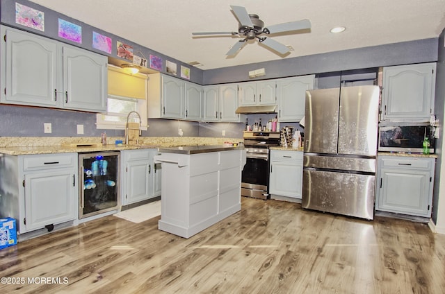 kitchen with appliances with stainless steel finishes, white cabinets, light wood-type flooring, and beverage cooler