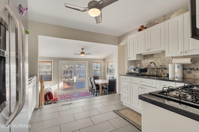 kitchen with white cabinetry, ceiling fan, stainless steel fridge, and backsplash