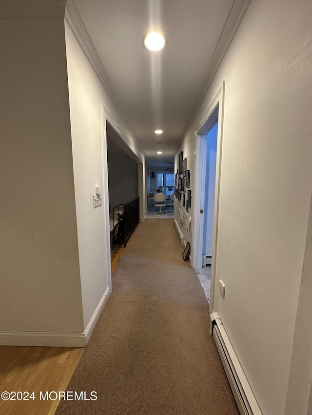 hall with crown molding, a baseboard radiator, and light carpet