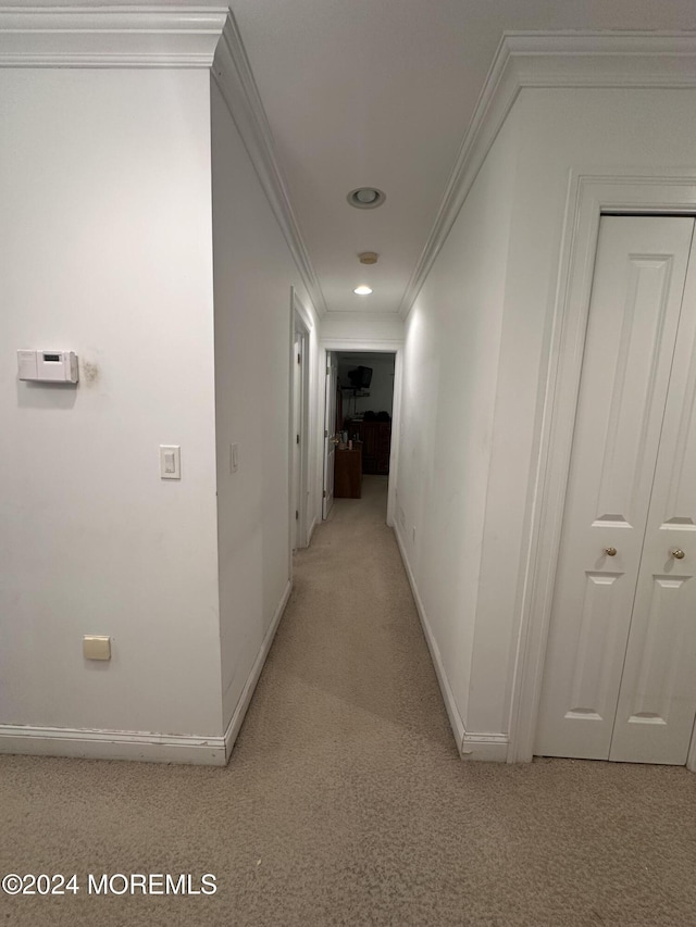 hallway featuring crown molding and light colored carpet