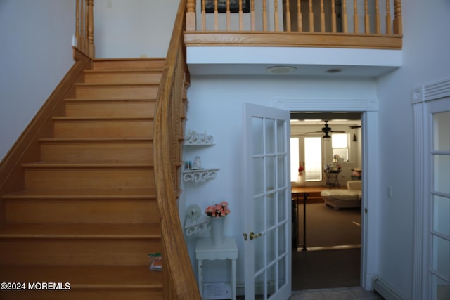 staircase with a towering ceiling and baseboard heating