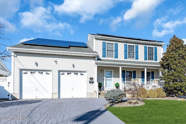 view of front of property with a garage, a front yard, solar panels, and a porch