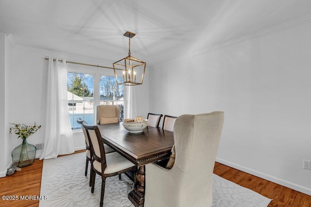 dining space with crown molding, an inviting chandelier, and light hardwood / wood-style flooring