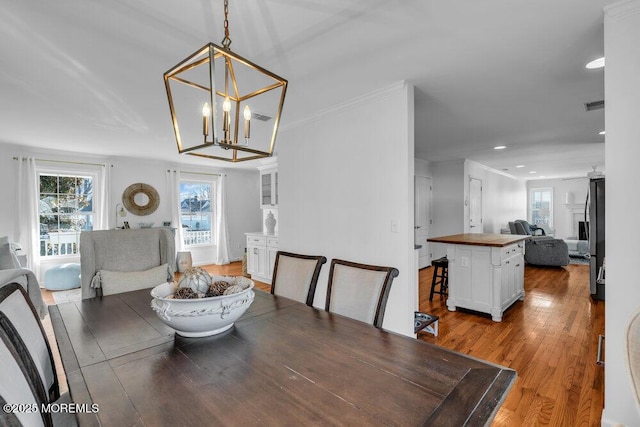 dining area featuring hardwood / wood-style flooring, ornamental molding, and a chandelier