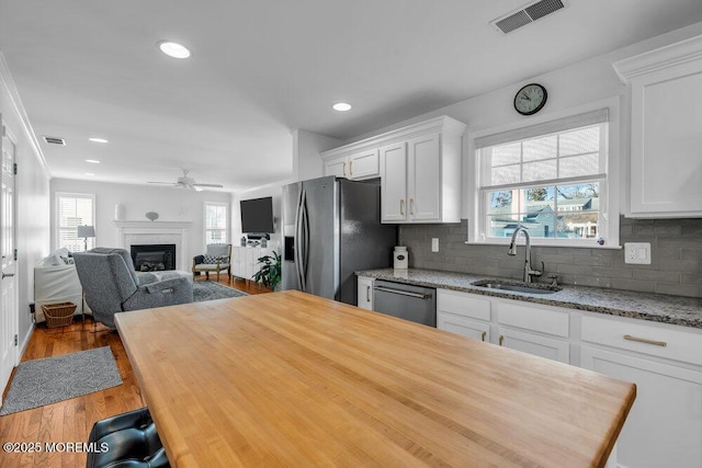 kitchen featuring tasteful backsplash, white cabinetry, sink, light stone counters, and stainless steel appliances