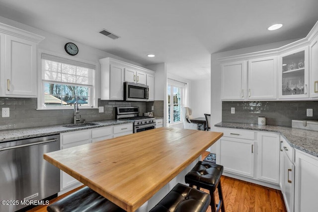 kitchen with light stone counters, stainless steel appliances, sink, and white cabinets